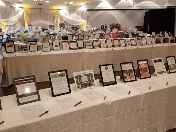 A long table of framed silent-auction items and gift baskets