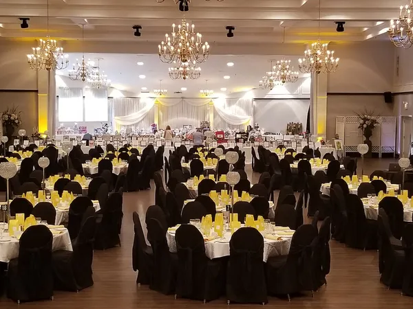 Round tables set with yellow napkins and black chair covers before the gala