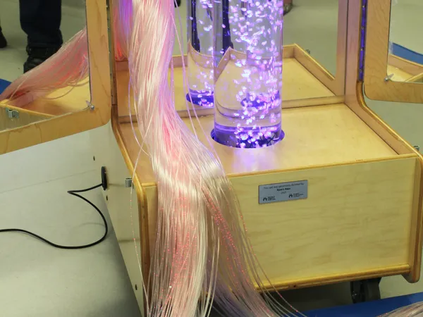 Close-up of the Snoezelen cart, with purple-lit bubble tubes and fibre-optic strands draped over the wooden base