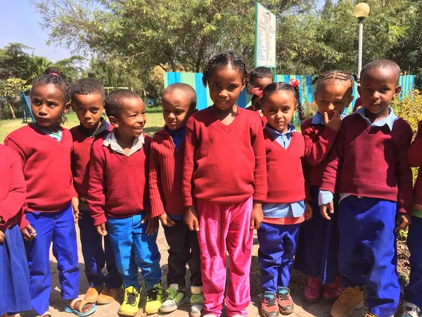 A group of young students in red school jumpers standing together outdoors