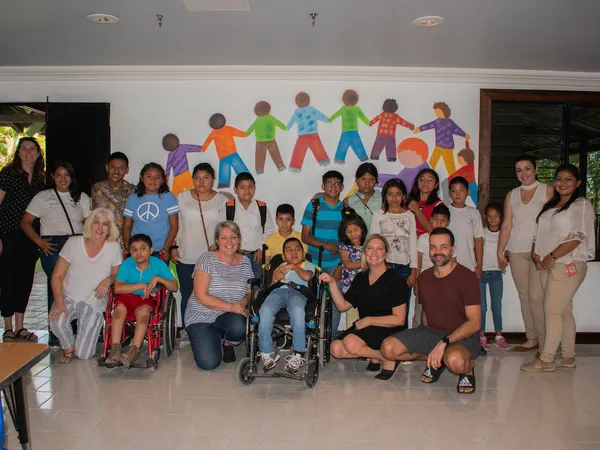 Students, teachers and visitors gathered in front of a mural of paper-chain children in the Special Needs Education classroom at Liberty College