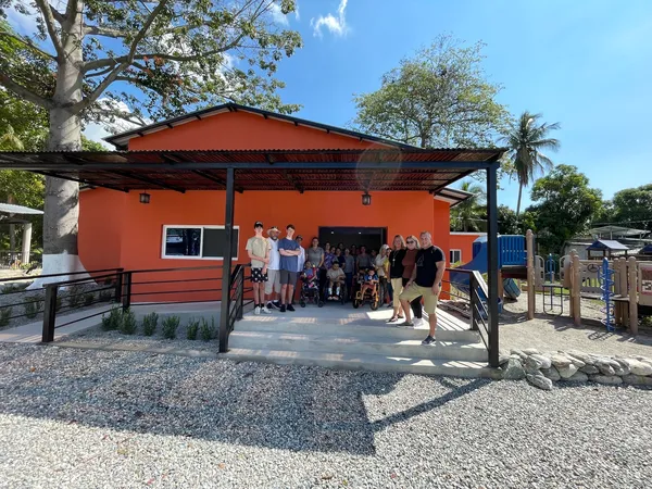 Visitors standing on the covered porch of Ryan’s Place, an orange care centre with an accessible ramp