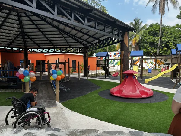 The covered inclusive playground with rubber flooring, artificial turf and a red spinner, decorated with balloons